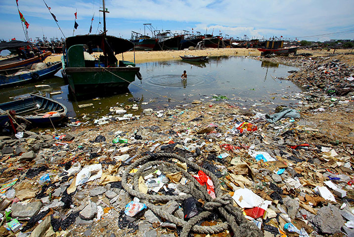 24 hours in pictures: Anquan, China: A boy swims in the polluted sea by the rubbish-strewn beach 