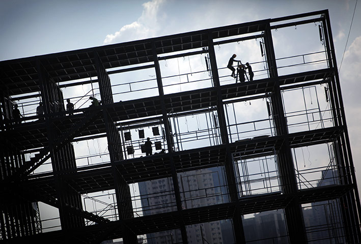 24 hours in pictures: Singapore: Workers are framed in the grid structure of a building