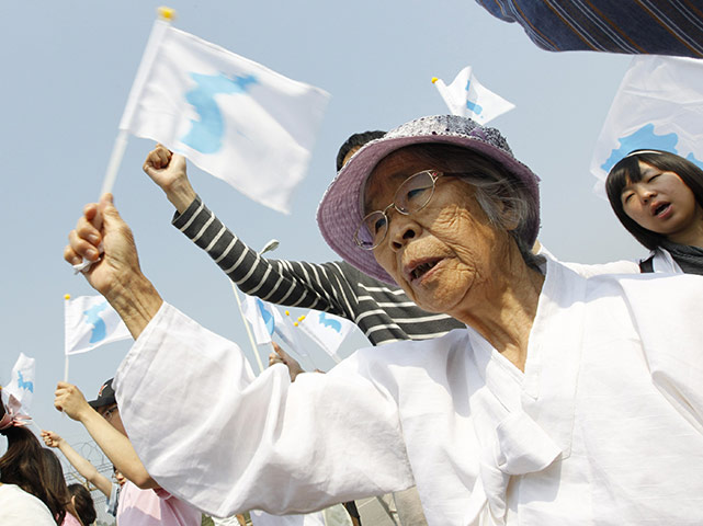 24 hours in pictures: Paju, Korea: A woman waves a unification flag as she takes part in a rally