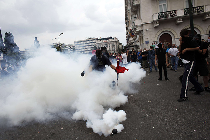 Protests in Greece: A protester attempts to kick away a tear gas grenade