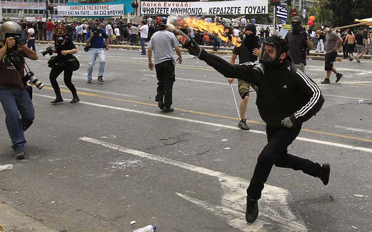 Protests in Greece: A demonstrator throws a petrol bomb to riot police 