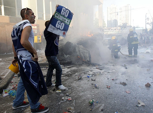 Vancouver riots: Firefighters put out the flames of a burning vehicle as Canucks fans react