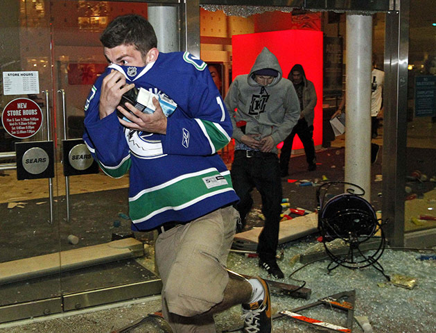 Vancouver riots: Vancouver Canucks fans loot through the smashed windows of a Sears