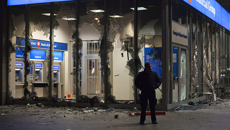 Vancouver riots: A security guard stands outside a bank damaged in the riots 
