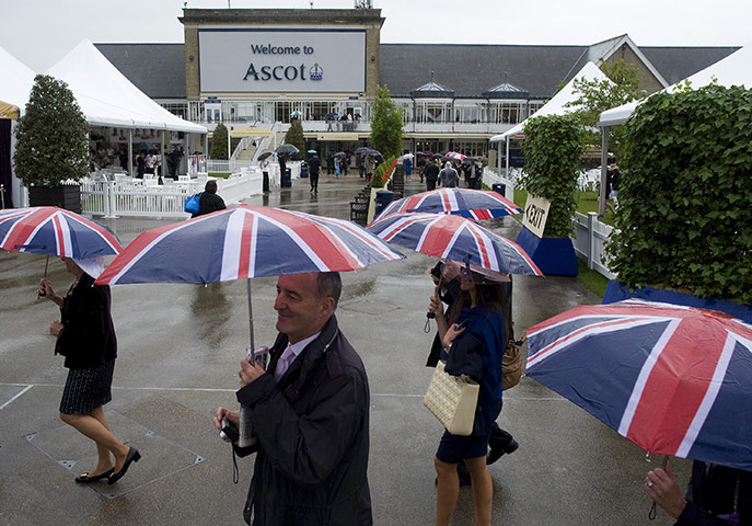 Ascot Ladies day: Racegoers shelter under umbrellas as rain falls during Ladies Day