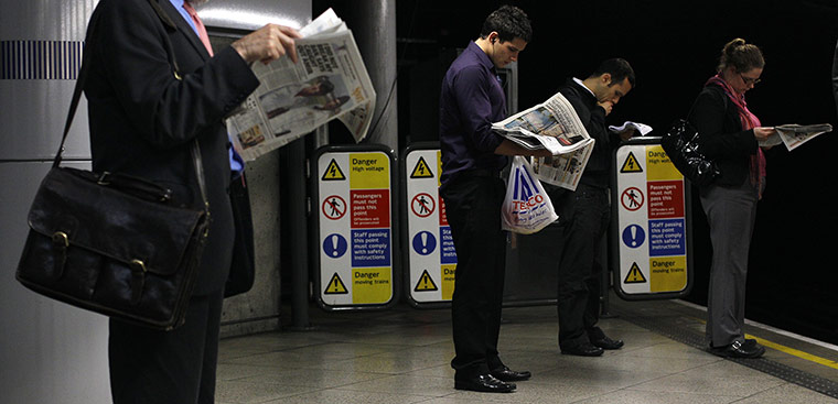 Week in Business: Commuters read evening papers as they wait for an underground train, London