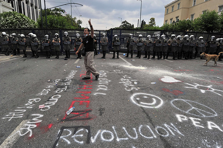 Week in Business: A protestor stands in fron of riot police protecting the parliament 