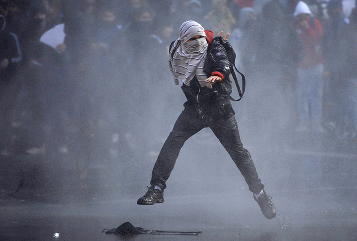 24 hours in pictures: A masked demonstrator runs from a water canon, Chile