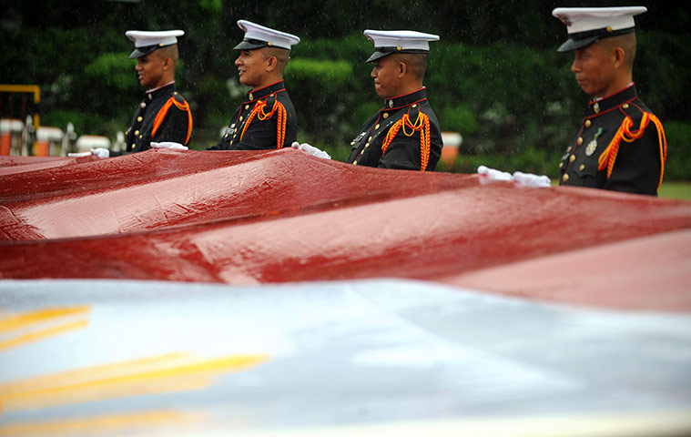 24 hours: Manila, Philippines: Philippine honour guards hold a wet flag in the rain
