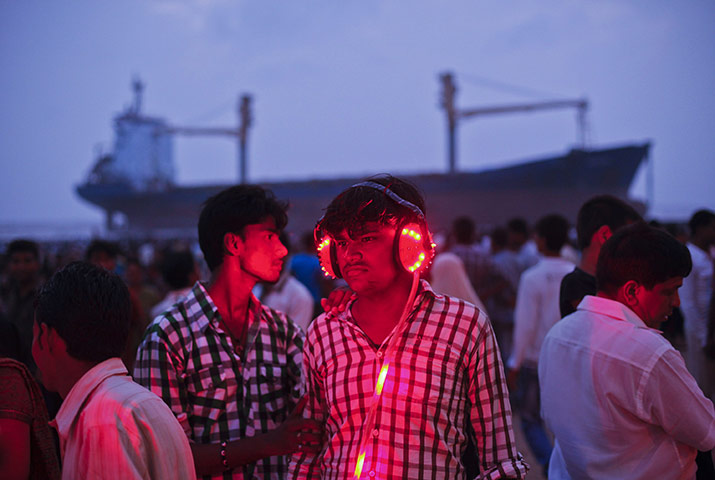 24 hours: Mumbai, India: A man wears headphones to listen to a fortunetelling machine