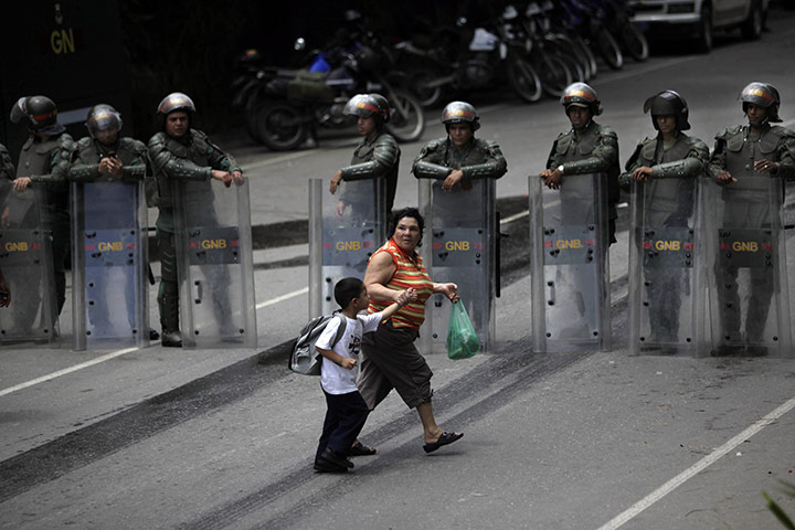 24 hours in pictures: Guatire, Venezuela: A woman and child pass National Guard soldiers 