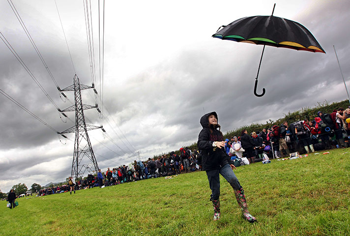 Glasontbury arrivals: A young girl loses her umbrella alongside festival-goers as they queue 