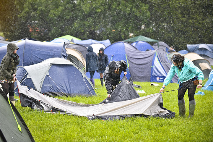 Glastonbury arrivals: Festival-goers wear waterproof clothing as they struggle to put up tents