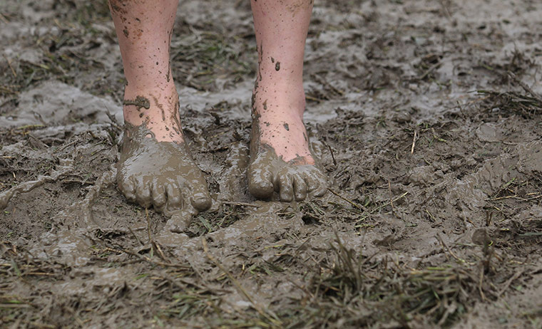 Glastonbury day 1: A festival goer braves the mud in bare feet as she arrives 