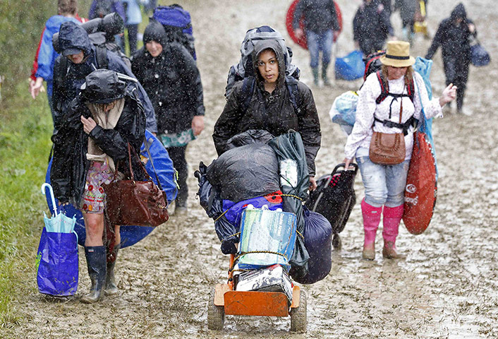 Glastonbury day 1: Festival goers push their belongings through muddy fields 