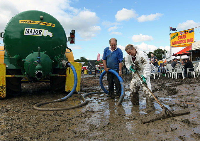Glastonbury day 1: Workers attempt to sweep away and suck up some of the mud on the paths 