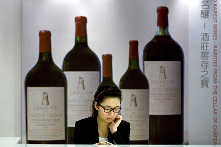 Week in Business: A Christie's staff member sits near an ad for Chateau Latour fine wines