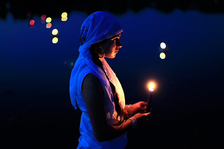 24 hours in pictures: A Gypsy maiden holds a candle during a ritual, Bucharest