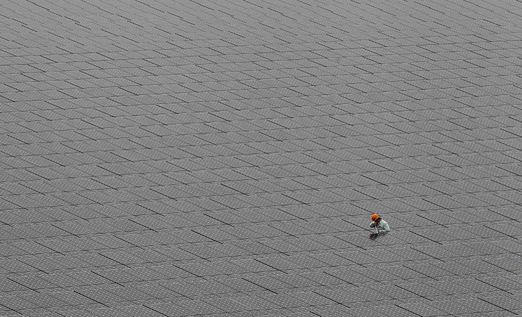 24 hours in pictures: a worker walks among solar panels in Kawasaki