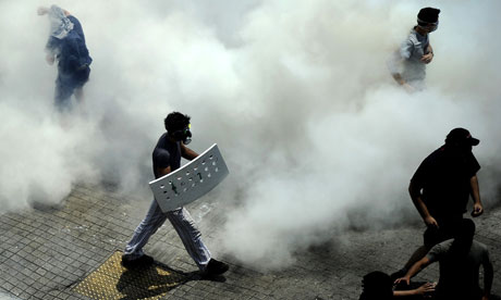 Demonstrators wearing gas masks walk amid tear gas during clashes with police, Greece