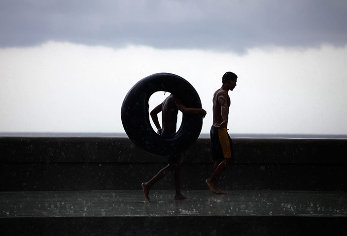 24 hours in pictures: Havana, Cuba: Youths walk during a storm on seafront boulevard, El Malecon