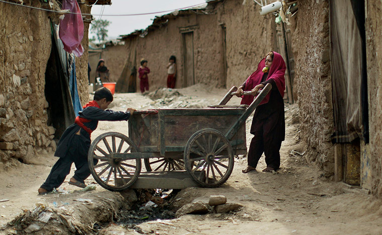 24 hours in pictures: Pakistani children try to move a cart in an alley of a slum area