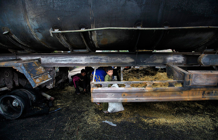 24 hours in pictures: A boy searches for metal scrap under an oil tanker, Afghanistan