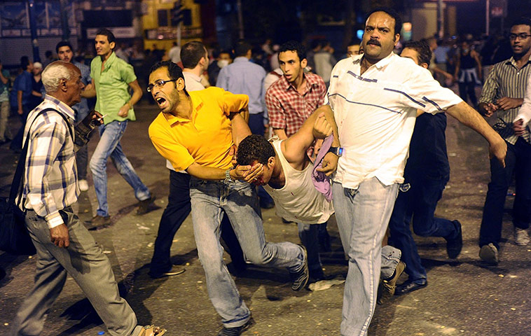 24 hours in pictures: Egyptians carry a young man who was injured during clashes, Cairo 