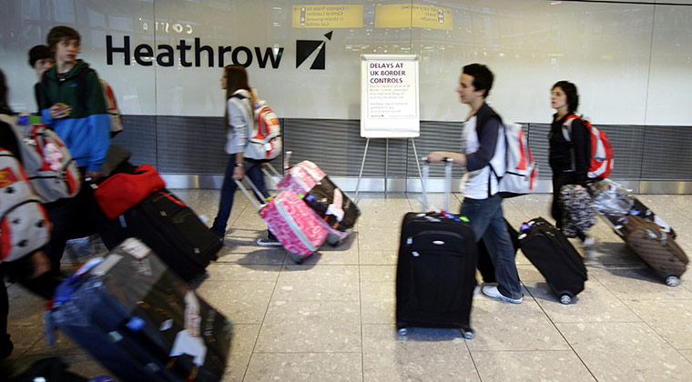 Public sector strikes: Passengers walk past an  information sign in arrivals at Border Control