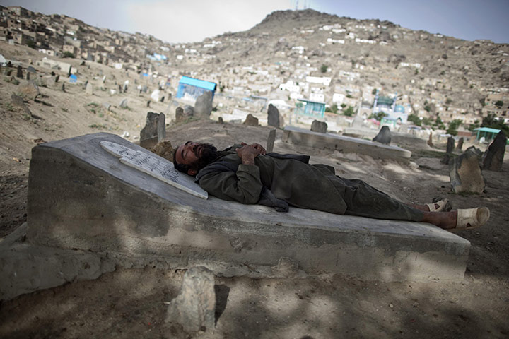 24 hours: Kabul, Afghanistan: An Afghan man sleeps on a grave at a cemetery