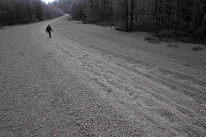 Volcano in Chile: A policeman walks along a road covered with pumice rocks