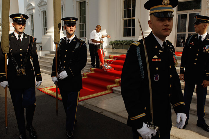 24 hours in pics: A worker, surrounded by members of an honour guard team, White House