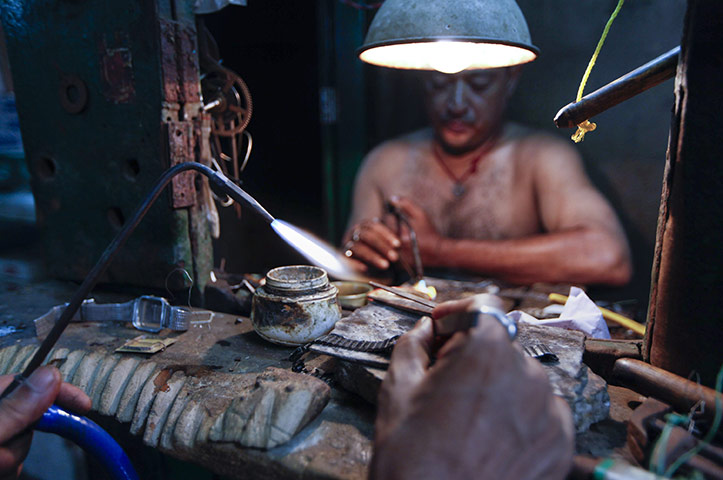 24 hours: Kolkata, India: A man repairs a wrist watch at his workshop 