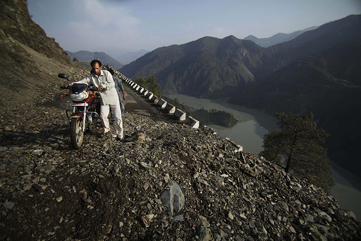 24 hours: Doda-Batote highway, India: A man pushes his motorcycle past a landslide