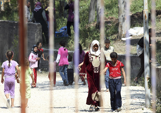 Syrian Refugees: Refugees walk behind the fence of a refugee camp