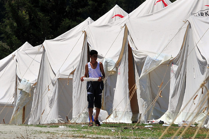 Syrian Refugees: A Syrian refugee walks besides tents