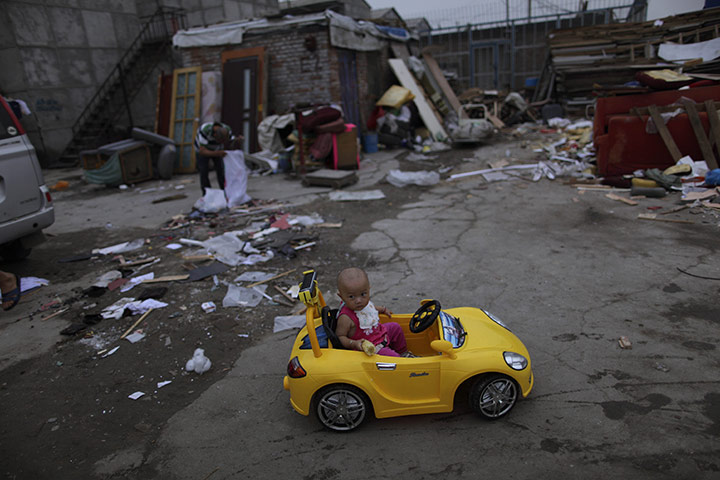 Luxury cars in China: A girl plays in a car, modelled on a Porsche, in a hutong in Beijing