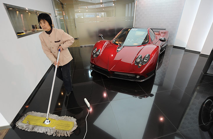 A cleaner sweeps the floor in a luxury car showroom in Beijing