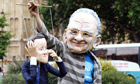 A protester dressed as Rupert Murdoch holds a puppet of David Cameron