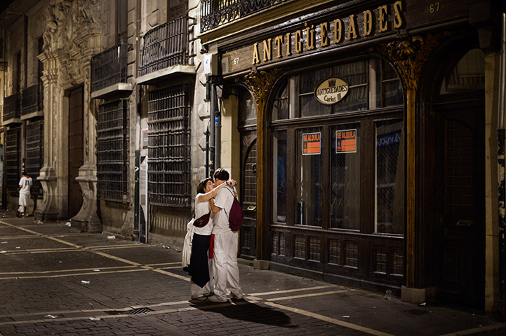 24 hours in pictures: Revelers embrace before the final running of the bulls, Pamplona, Spain