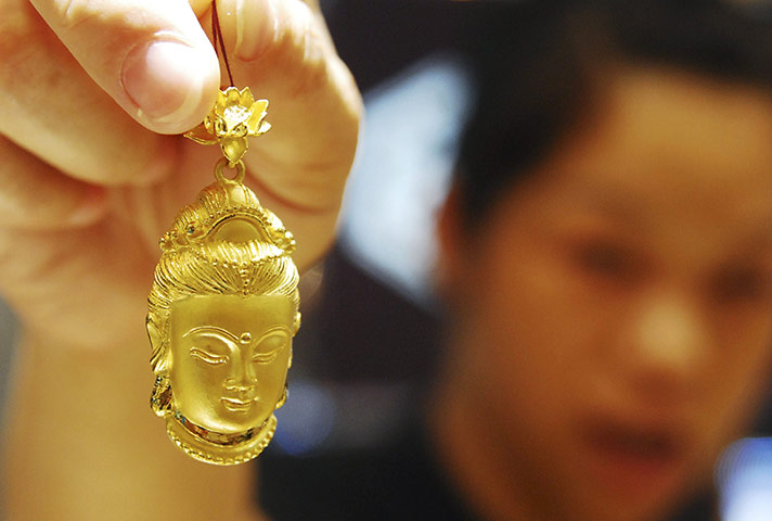 Week in Business: A sales assistant holds a gold accessory in the shape of Buddhist goddess