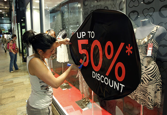 Week in Business: A woman sticks a discount sign on a clothing store window