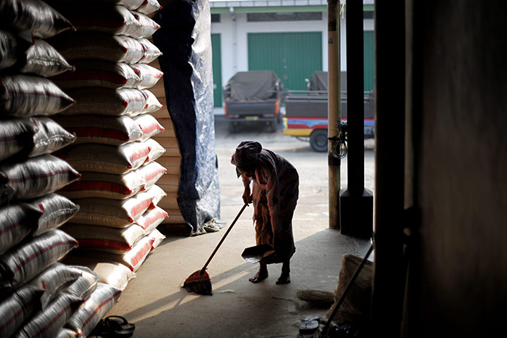 24 hours in pictures: An Indonesian woman clear up rice from rice vendors stall floor