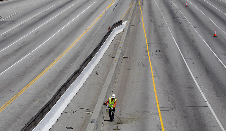 24 hours: Los Angeles, California, USA: A worker cuts weeds growing on Interstate 405