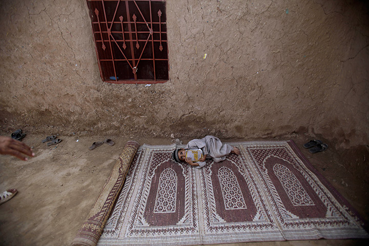 24 hours in pictures: Pakistani boy lies on a carpet outside a mosque