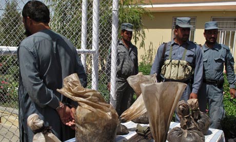 Afghan policemen stand guard as a handcuffed man is presented to the media, Lashkar Gah 18 July 2011