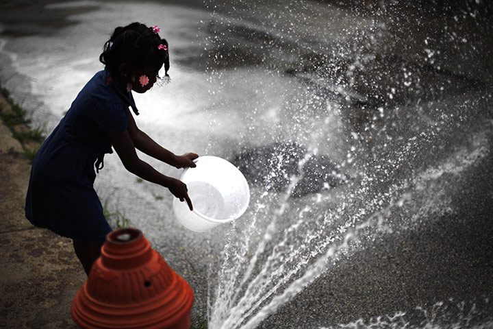 24 hours in pictures: A girls fills a bucket with water from a fire hydrant in Philadelphia, USA