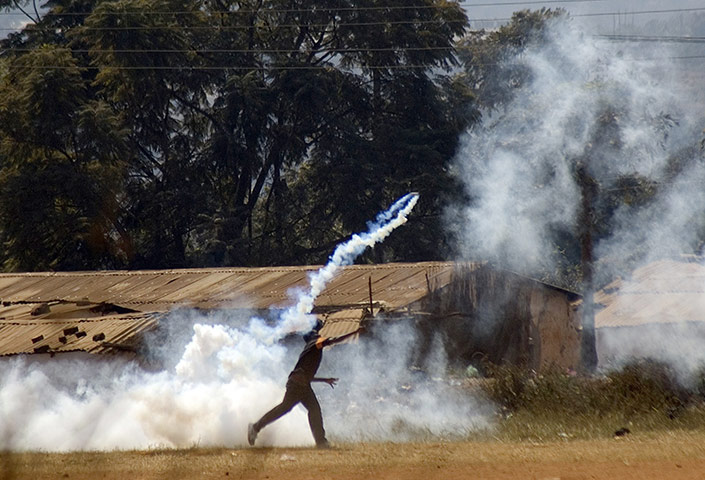 Malawi protests: A protester throws back a teargas canister fired by police