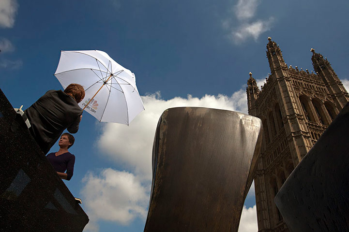 College Green media: An American tv news reporter is protected by an umbrella while she waits