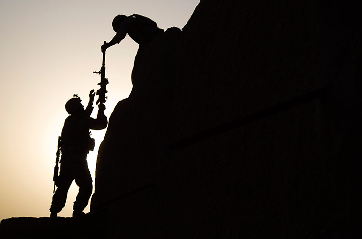 24 hours in pictures: US marines passes a gun to fellow soldier, Afghanistan
